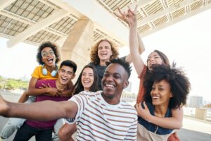 Group of friends having fun in the city. Young interracial students taking a selfie.